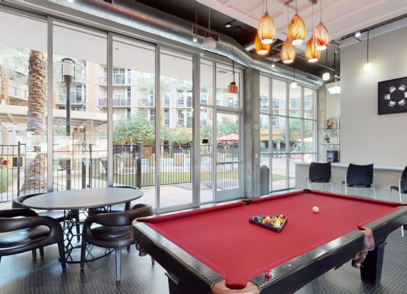 a red pool table in a room with large windows