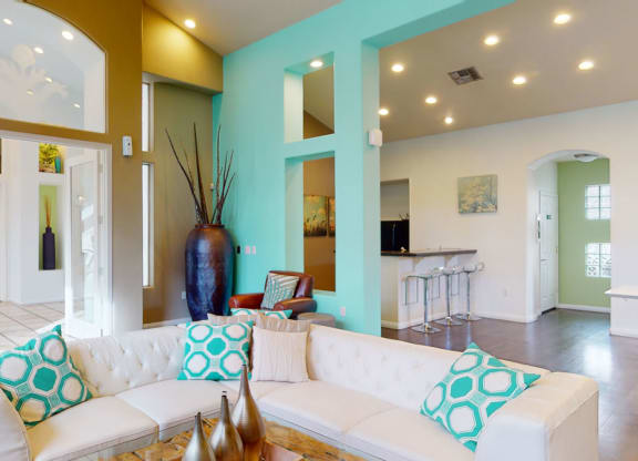 Modern living room here at The Hawthorne Apartments with aqua and beige walls, white sectional sofa with turquoise pillows, and a tall vase. Bright, open, and inviting atmosphere.