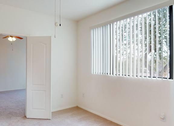 A room with a white door and a window with blinds.