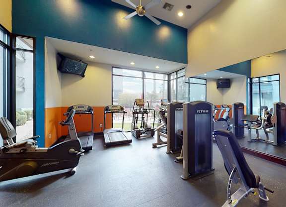 A gym with a variety of equipment including treadmills, weights, and exercise machines.