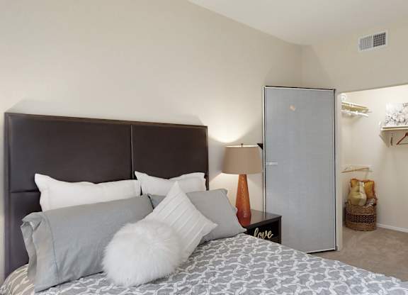 A bedroom with a bed, a nightstand, and a fridge.
