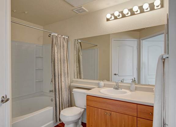 A bathroom with a white toilet, sink, and shower.