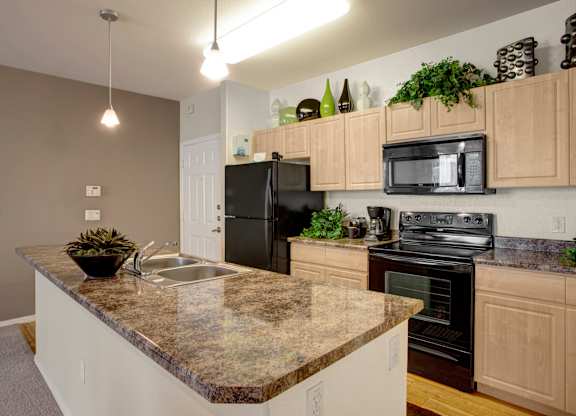 A kitchen with granite countertops and black appliances.
