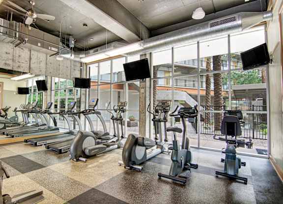 A gym with treadmills, exercise bikes, and a checkered floor.