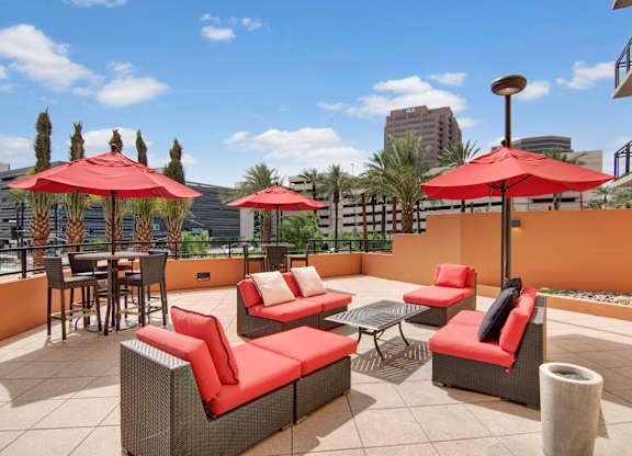A patio with red cushions and umbrellas.