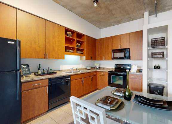 A kitchen with wooden cabinets and a black refrigerator.