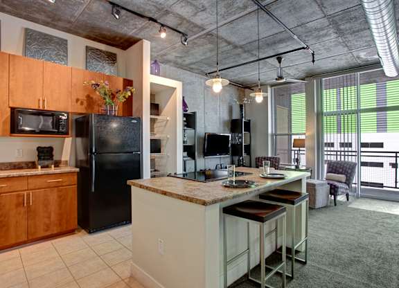 A kitchen with a black refrigerator and a black microwave.