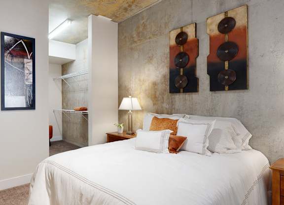 A bedroom with a bed, two lamps, and two pictures on the wall.