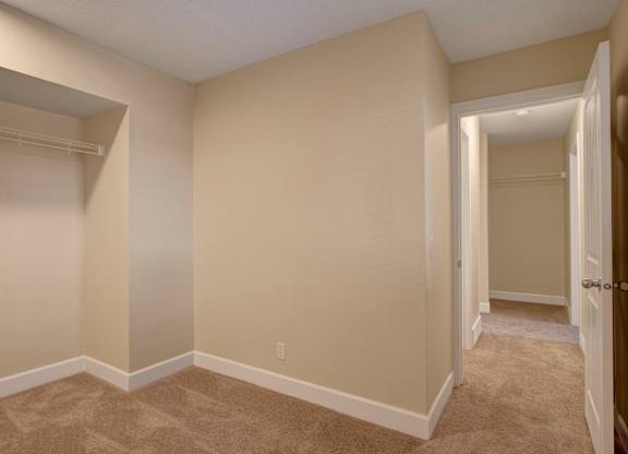 A spacious bedroom here at 3600 Brentwood with soft neutral carpet, clean walls, and a large open closet for easy storage, with a hallway leading to additional rooms.