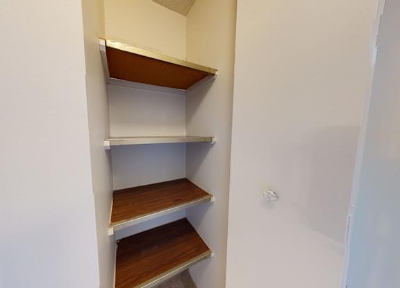 A convenient storage nook here at Cambridge West with built-in wooden shelves, offering practical space for pantry items, cleaning supplies, or extra household storage.