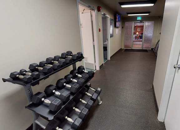 A convenient fitness area here at Cambridge West with a full set of free weights, rubber flooring, and bright overhead lighting, located near the community lounge for easy access.
