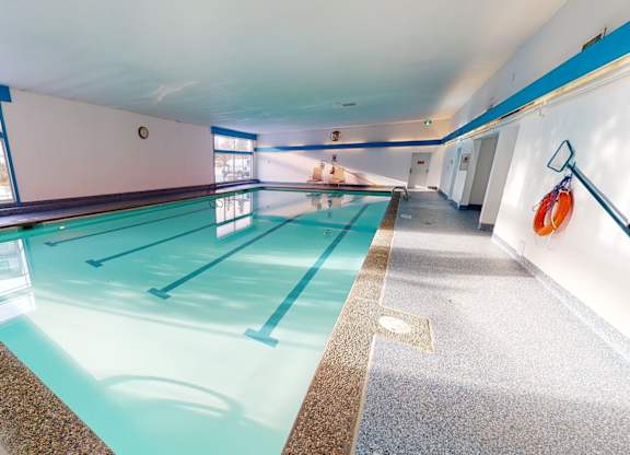 A bright indoor swimming pool here at Cambridge West with clear water, lap lanes, and wide deck space, featuring large windows for natural light and a clean, relaxing atmosphere.