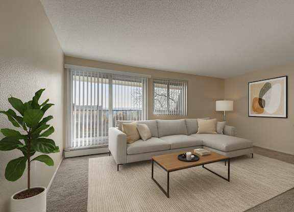 A bright living room here at Cedar Gardens featuring a spacious light gray sectional with neutral throw pillows, a warm wood coffee table, and a soft area rug, complemented by large windows, simple wall art, and lush greenery for a cozy, welcoming feel.