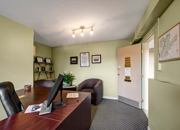 A comfortable leasing office here at Gateway Square with soft green walls, a wooden desk, cozy seating, framed certificates, and warm lighting creating a friendly and professional space.