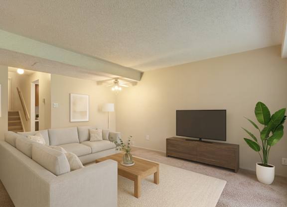 A bright, modern living room here at Lakewood Heights with a light gray sectional sofa, a wooden coffee table, neutral wall art, soft carpeted flooring, and a media console with a TV, creating a warm and inviting atmosphere.