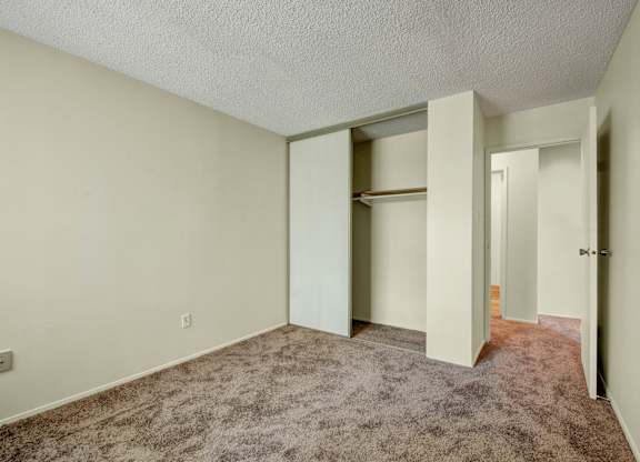 A comfortable bedroom at Lakewood Heights featuring soft carpet, neutral walls, a sliding-door closet for easy storage, and a simple layout that’s easy to personalize.