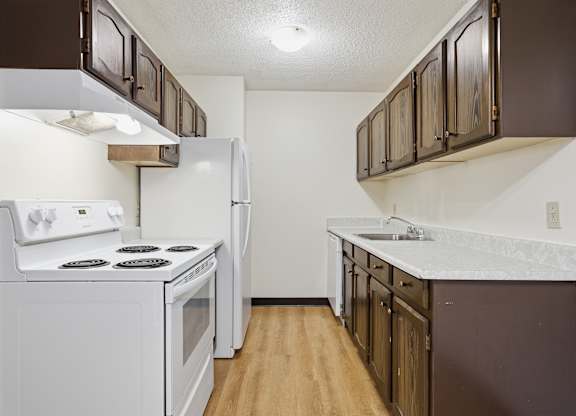 A kitchen with white appliances and brown cabinets.