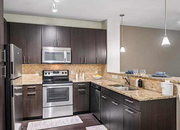 A modern kitchen with dark brown cabinets and stainless steel appliances.