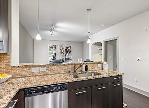 A kitchen with a granite countertop and stainless steel appliances.