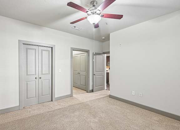 A room with a ceiling fan and carpeted floor.