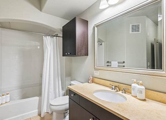 A bathroom with a white toilet, a sink, and a bathtub with a shower curtain.