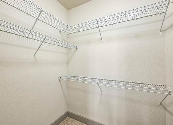 A white wall with three metal shelves.