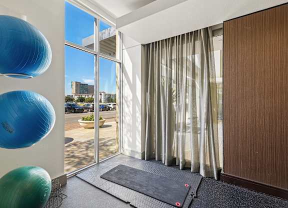 A room with a mat on the floor and three exercise balls on the wall.