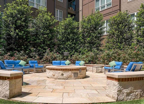 A patio with blue chairs and a fire pit.