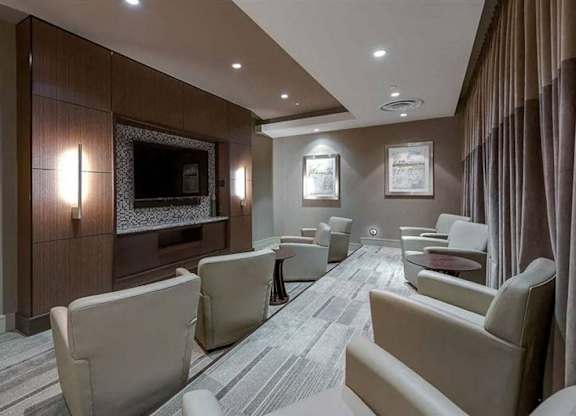 A modern living room with a grey carpet and beige chairs.