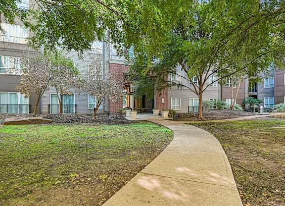 A walkway leads through a grassy area in front of apartment buildings.