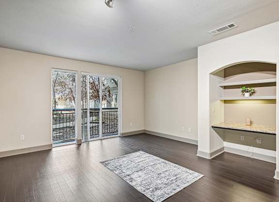 A spacious room with a sliding glass door and a rug on the floor.