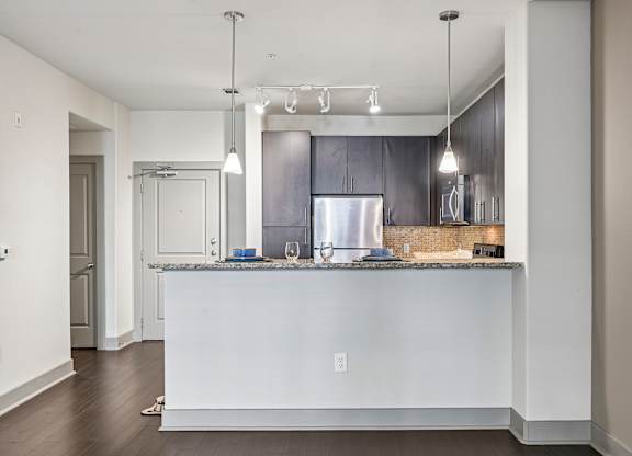 A modern kitchen with a white island and dark wood cabinets.