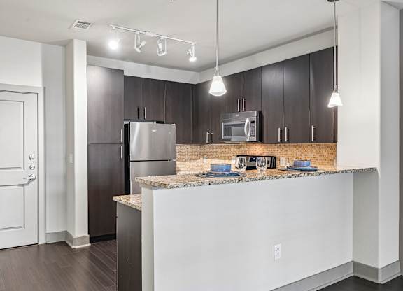 A kitchen with a refrigerator, microwave, and oven.