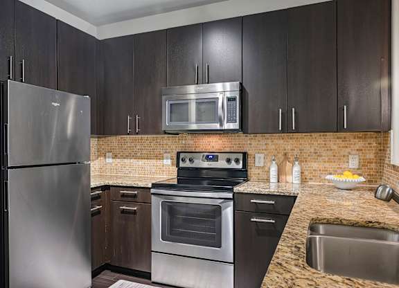 A kitchen with a stainless steel refrigerator, oven, and microwave.