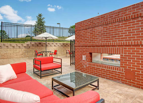 A red couch and table are on a patio.