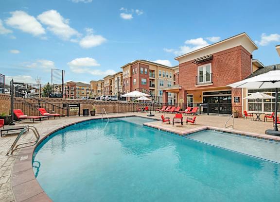 A swimming pool surrounded by red lounge chairs and umbrellas.