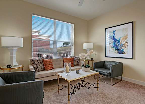 A living room with a sofa, armchair, and a painting on the wall.