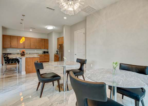 A modern dining room with a glass table and black chairs.