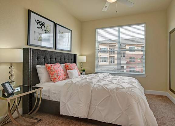 A bedroom with a large bed and a window with blinds.