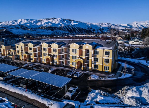 an aerial view of a large apartment complex with snow covered mountains in the background