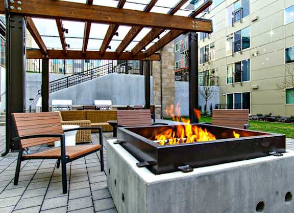 A fire pit with a wooden pergola above it.