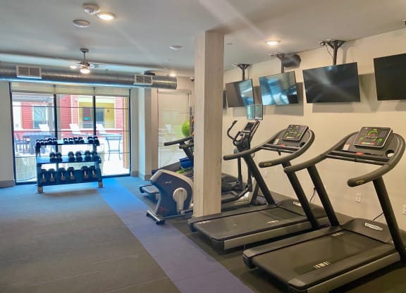 a gym with cardio machines and televisions on the wall