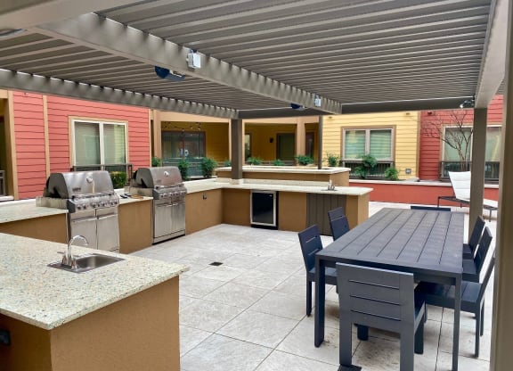 a patio with a table and chairs and a grill