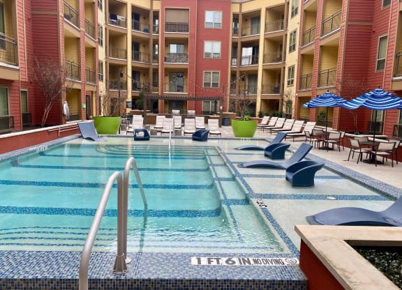 a swimming pool at an apartment building with chairs and umbrellas