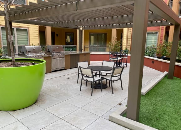 a patio with a table and chairs and a grill
