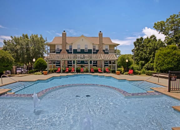 a large swimming pool with a house in the background