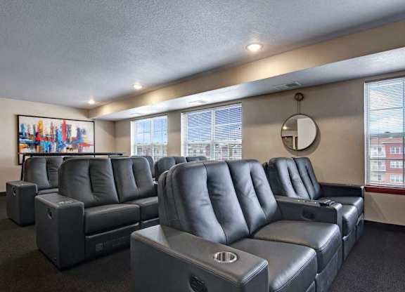 A private theater room here at Club at Heritage with plush reclining seating and built-in cup holders. Large windows and soft lighting create a comfortable space for movie nights and entertainment.