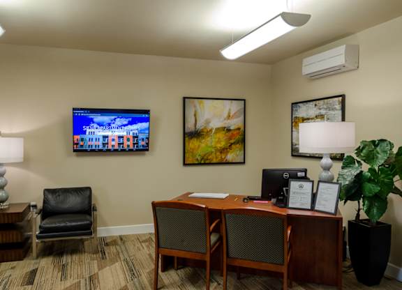 A room with a desk, chair, and a painting on the wall.