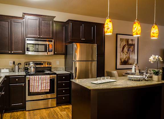 A kitchen with dark brown cabinets and a stainless steel refrigerator.