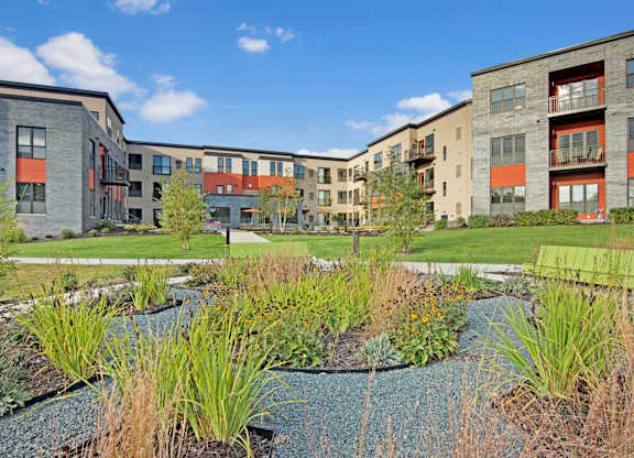 A modern apartment complex with a landscaped courtyard in the foreground.